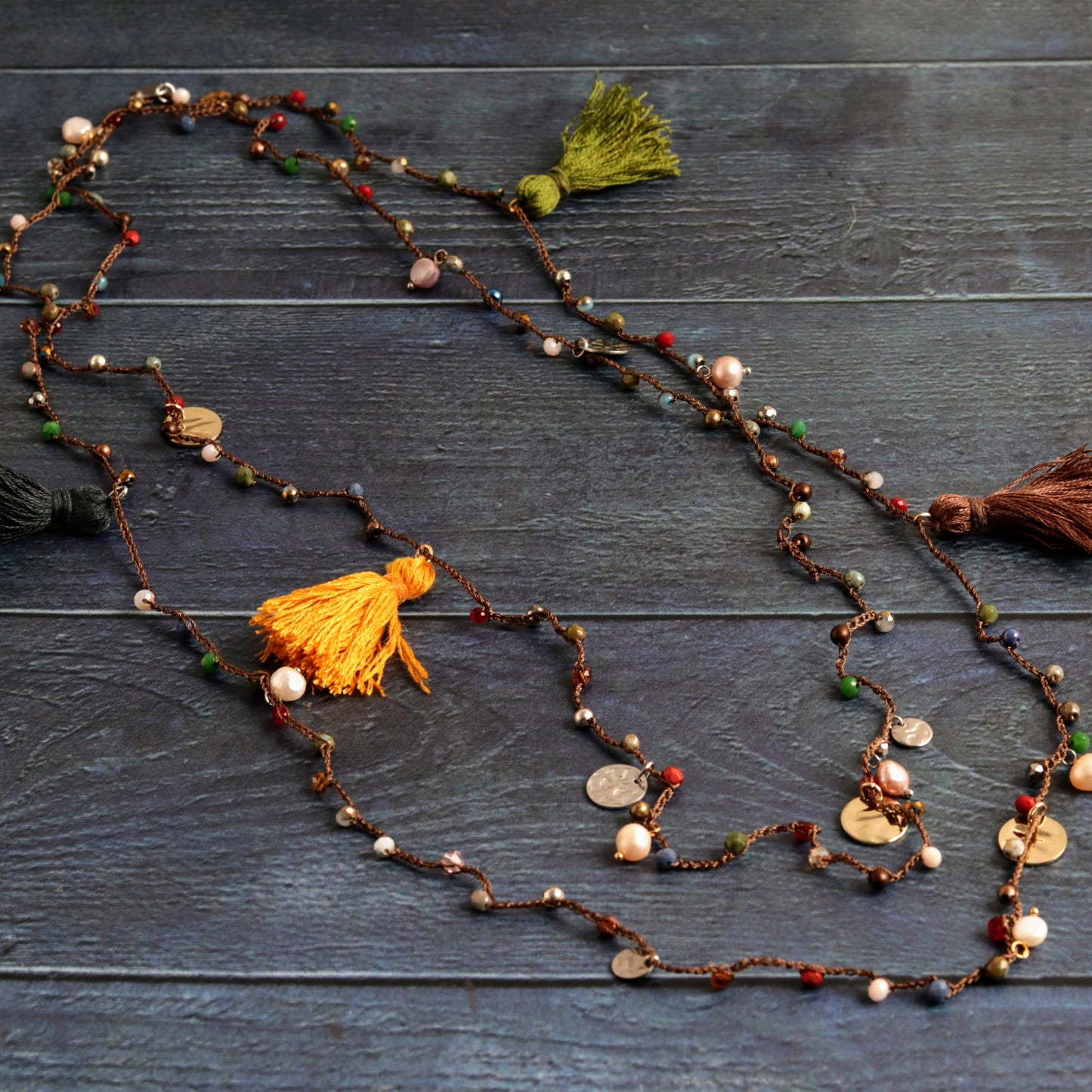 Long beaded necklace with tassels on a wooden surface