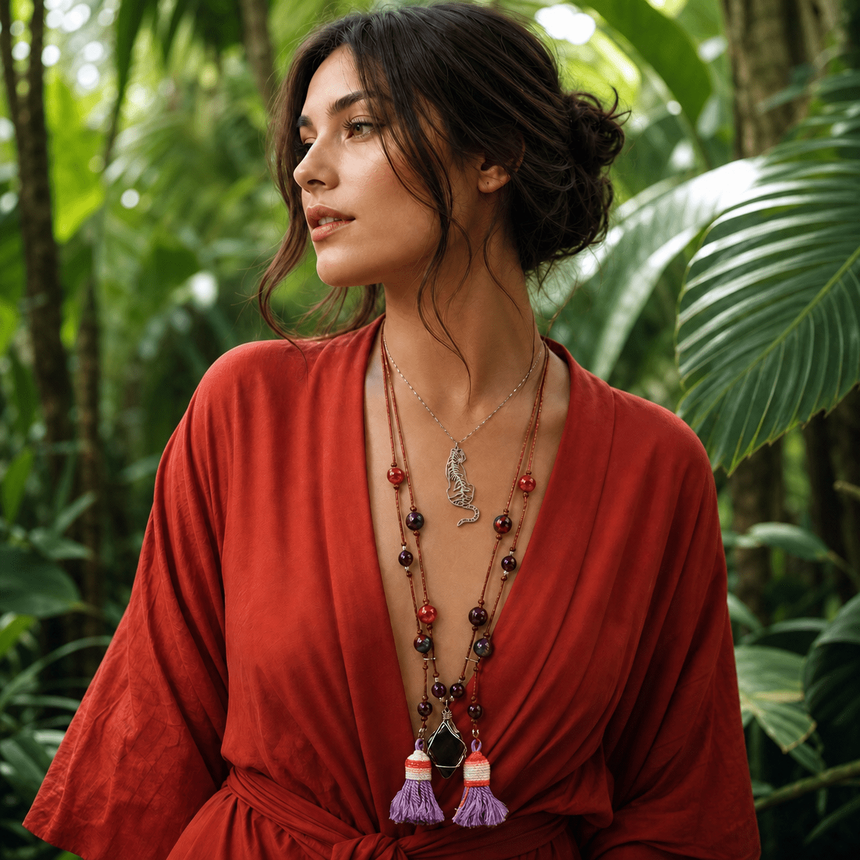 Woman in a red dress with a long necklace standing in a lush green forest