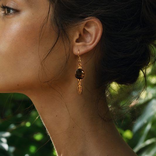 Woman with a bun and earrings against a green leafy background