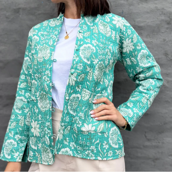 Woman wearing a teal floral jacket against a gray background