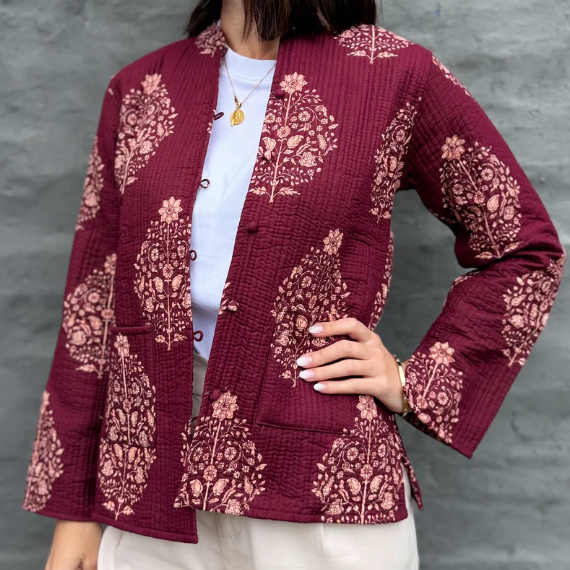 Person wearing a maroon patterned jacket against a gray background